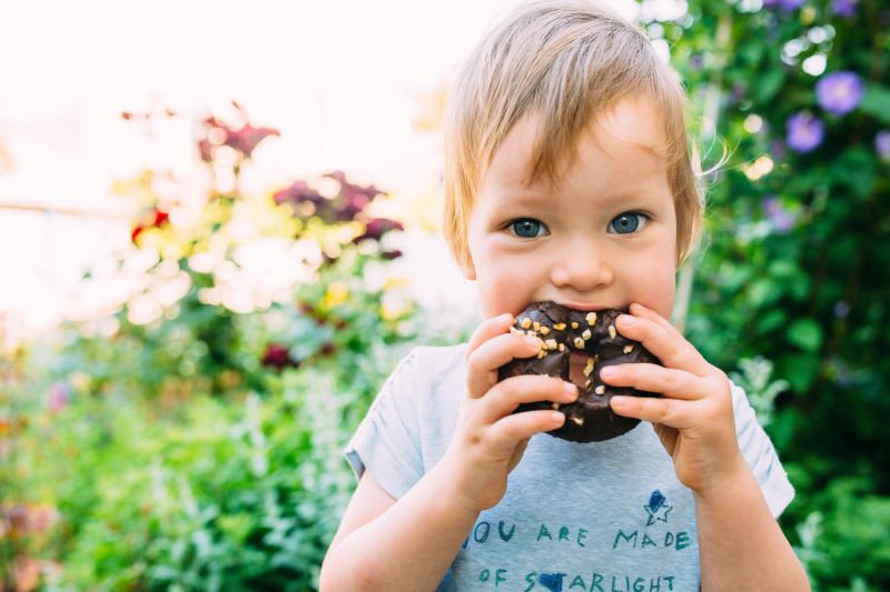 dziecko jedzące donuta z czekoladą