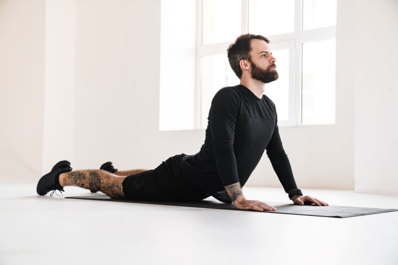 Ćwiczenia relaksacyjne - stretching na macie Mężczyzna robiący trening relaksacyjny rozciągający