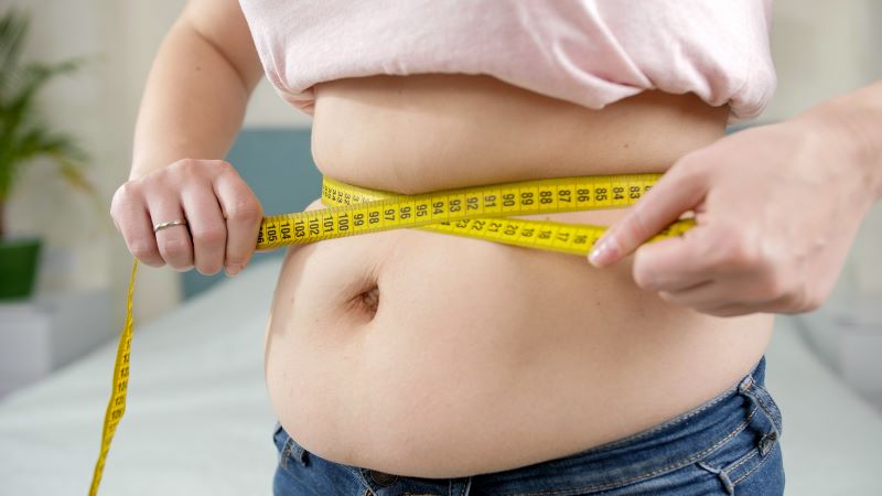 otyła kobieta mierząca brzuch jako motywacja do odchudzania