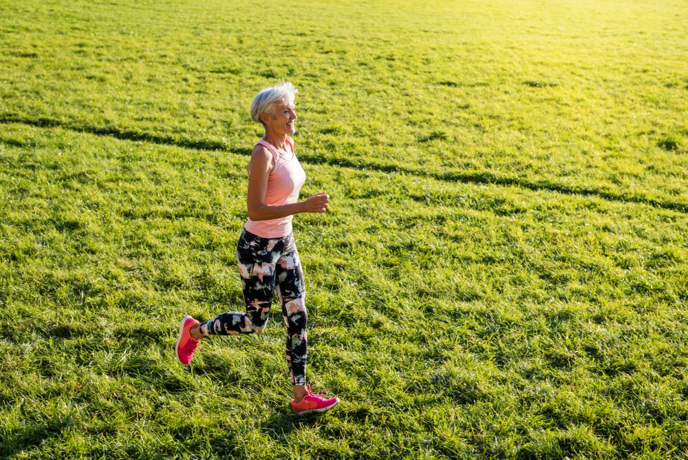 jak poprawnie biegać - starsza kobieta biegająca po trawie