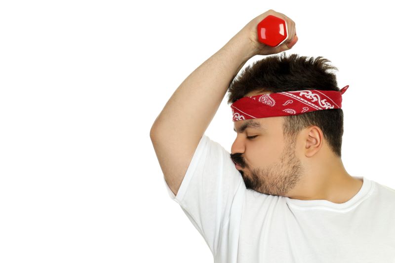 Samoakceptujący się męzczyzna męzczyzna tryzmający hantlę całujący swój biceps