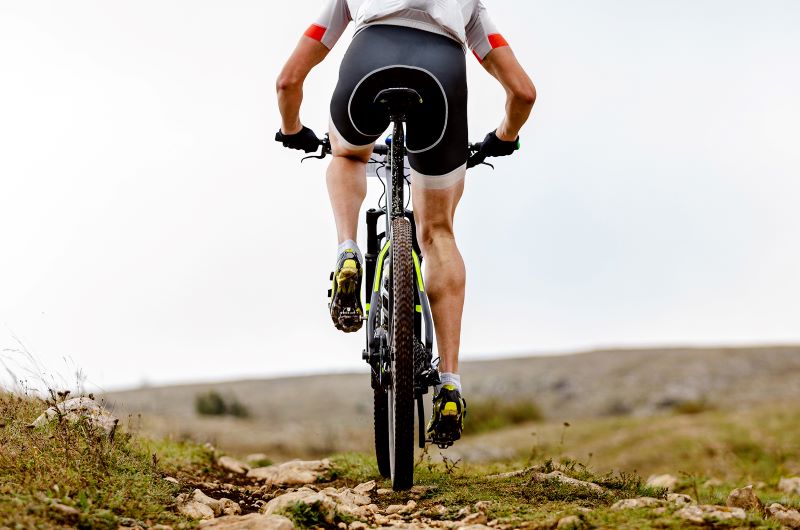 Rowerzysta z mocnymi łydkami bieganie czy rower na mięśnie - rowerzysta w terenie