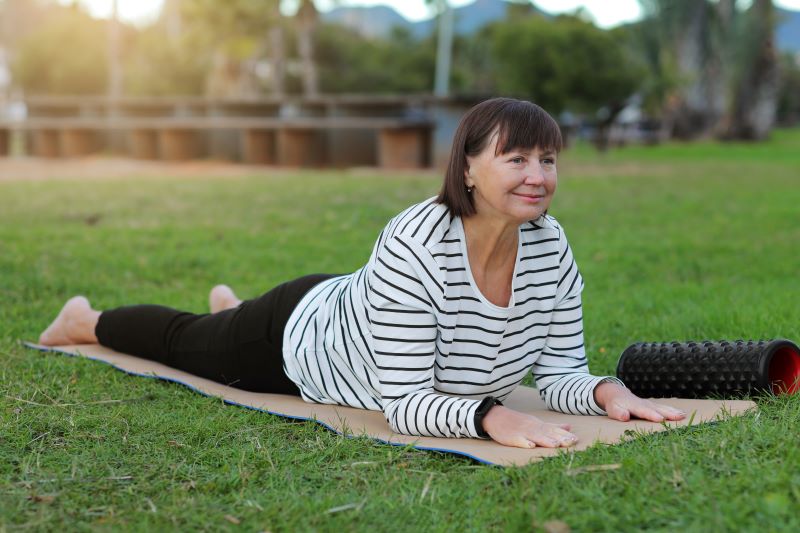 Pilates na macie w ogrodzie dojrzała kobieta uprawiająca pilates - ćwiczenia dla początkujących