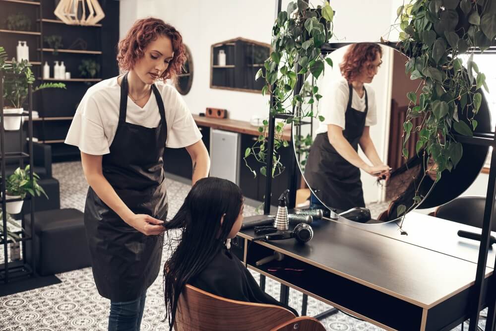fryzjerka obcinająca włosy dziecku dziecko na wizycie w salonie fryzjerskim